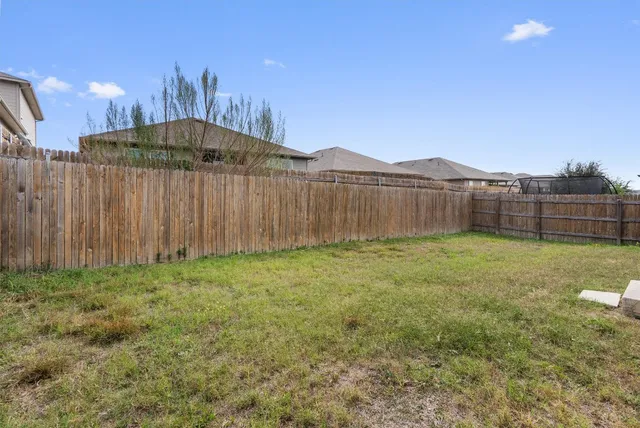 a view of a backyard with a barbeque and wooden fence