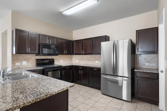 a kitchen with granite countertop a refrigerator and a sink