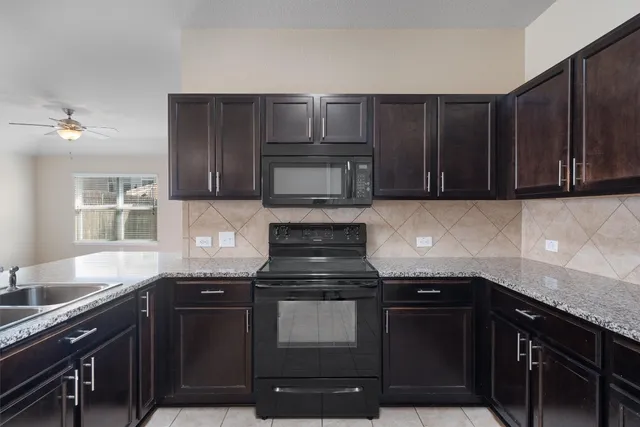 a kitchen with granite countertop wood cabinets and black appliances