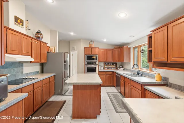 a large kitchen with stainless steel appliances kitchen island granite countertop a sink stove and refrigerator