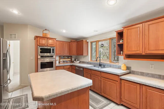 a kitchen with stainless steel appliances granite countertop a sink stove refrigerator and cabinets