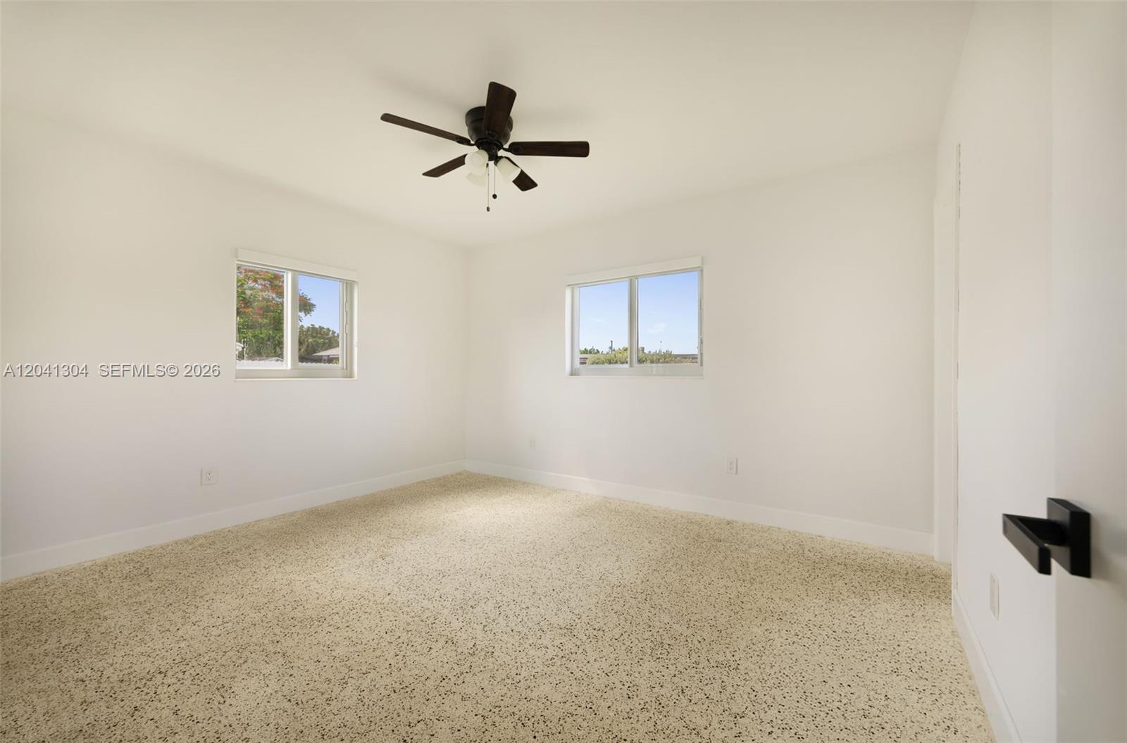 10340 Southwest 157th Street Miami, FL 33157 - Photo 10 of 24 Primary Bedroom – Spacious primary bedroom enhanced by multiple windows and a ceiling fan for year-round comfort. The airy design creates a relaxing retreat.