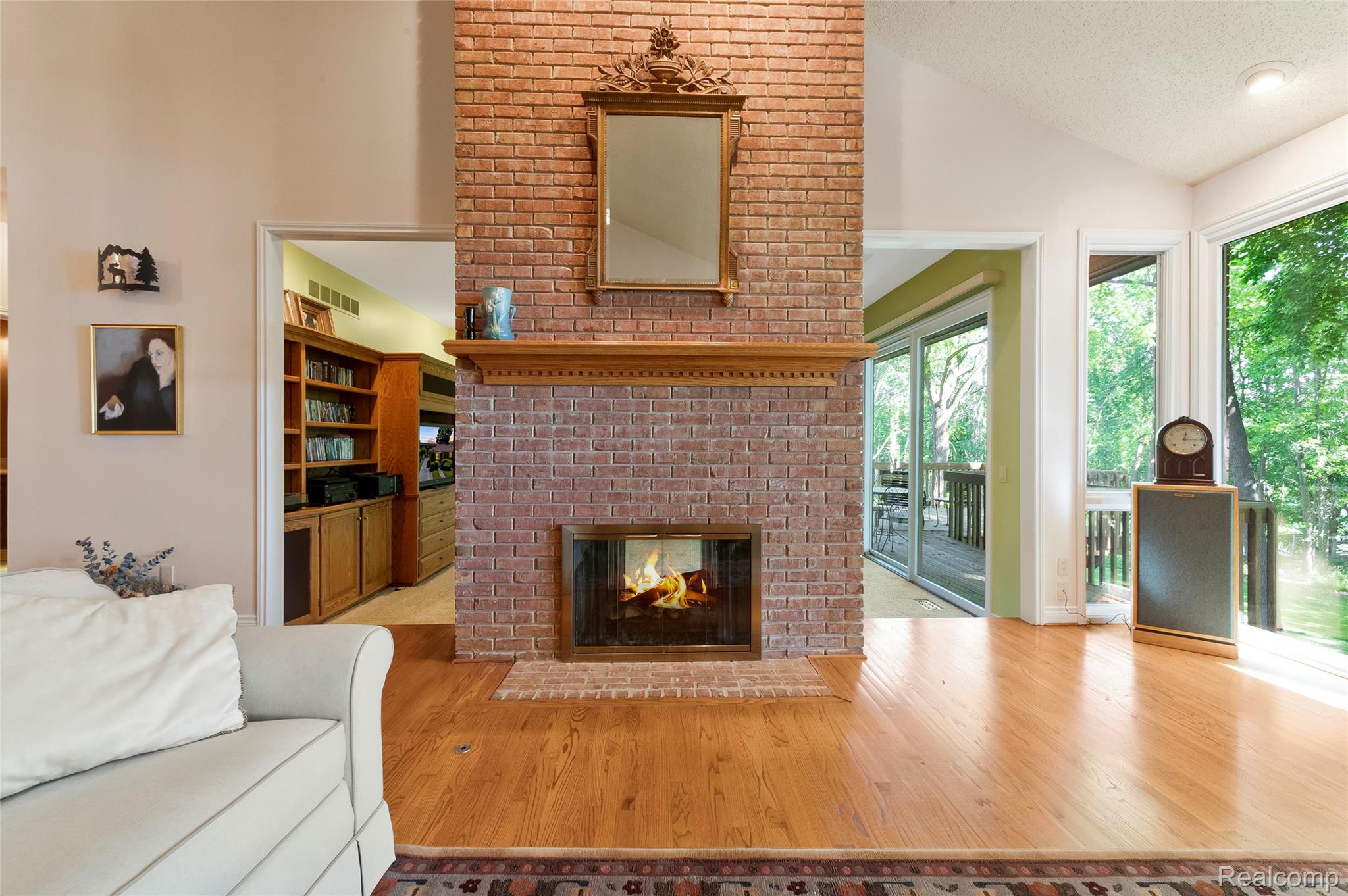 2323 Addaleen Road Highland, MI 48357 - Photo 31 of 70 Brick fireplace with a wood mantel and hearth, flanked by wood-finish flooring