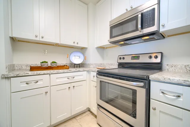 a kitchen with granite countertop white cabinets stainless steel appliances and a sink