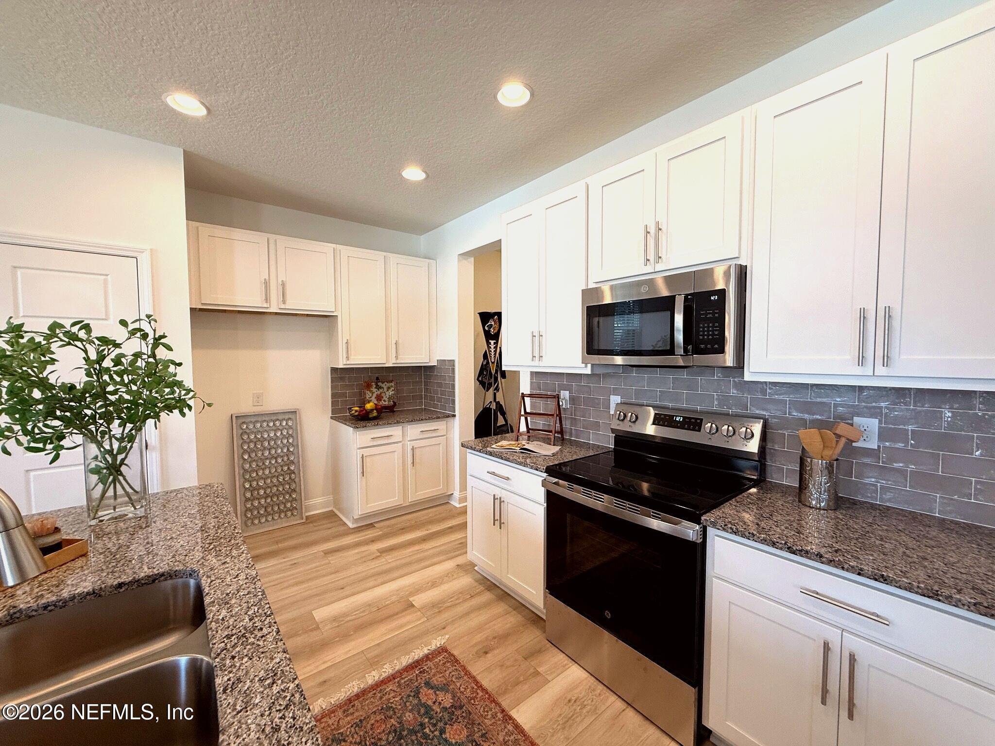 2913 Fleur Lane Jacksonville, FL 32205 - Photo 7 of 22 a kitchen with granite countertop a stove a sink a microwave a counter space and cabinets