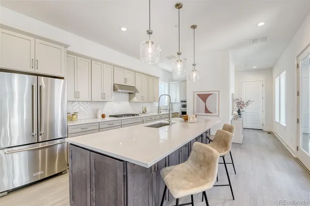 a kitchen with refrigerator a stove a sink and chairs