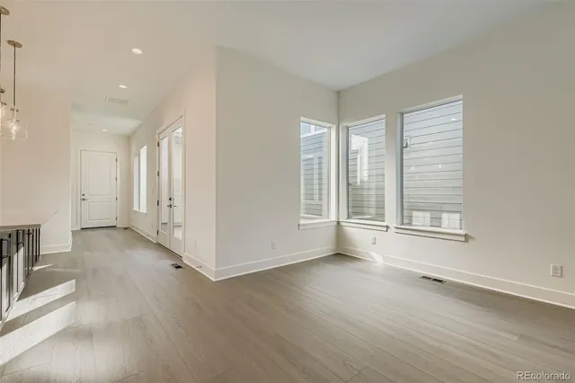 an empty room with wooden floor and windows
