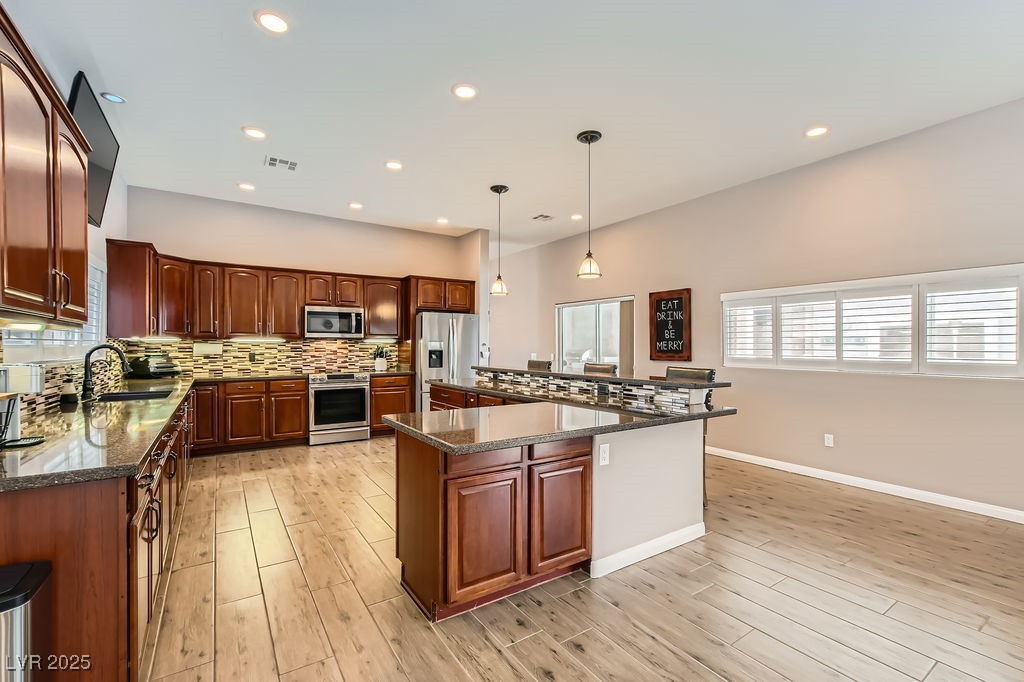 647 Foxhall Road Henderson, NV 89002 - Photo 16 of 82 Kitchen with backsplash, a sink, hanging light fixtures, light wood-type flooring, and stainless steel appliances
