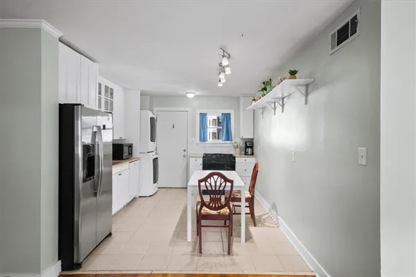 a kitchen with a refrigerator a dining table and chairs