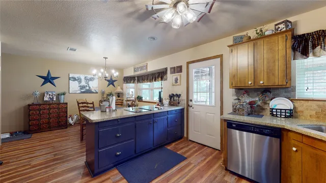 a kitchen with stainless steel appliances granite countertop a sink dishwasher stove and refrigerator with wooden floor