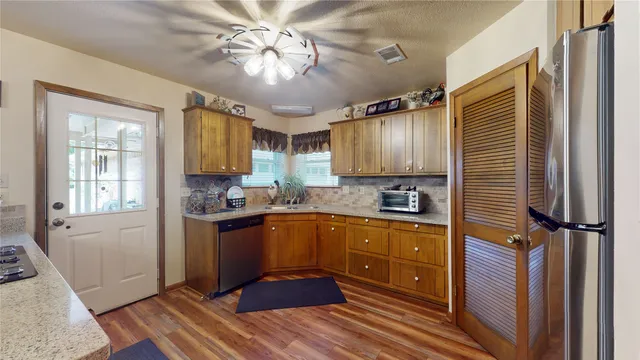 a kitchen with stainless steel appliances granite countertop a sink refrigerator stove and cabinets