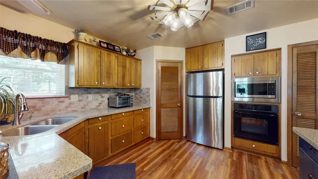 a kitchen with stainless steel appliances granite countertop a refrigerator a stove top oven a sink and dishwasher