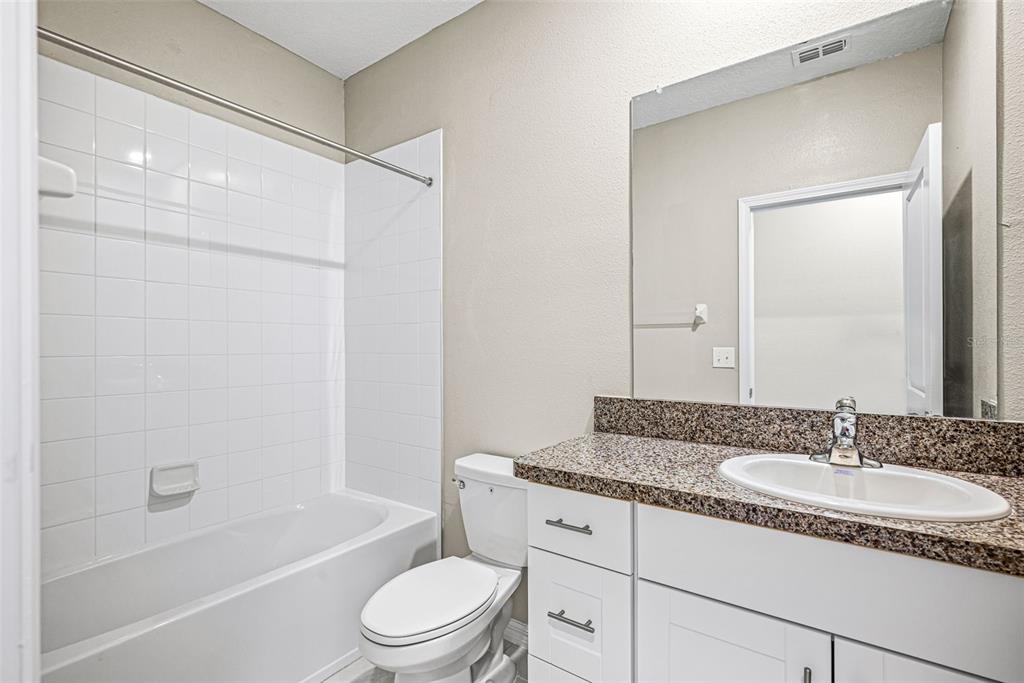 31945 Blue Passing Loop Wesley Chapel, FL 33545 - Photo 18 of 22 a bathroom with a granite countertop sink a toilet and shower