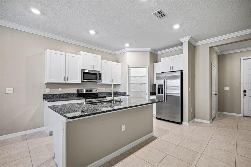 31945 Blue Passing Loop Wesley Chapel, FL 33545 - Photo 4 of 22 a kitchen with stainless steel appliances granite countertop a refrigerator and a stove top oven