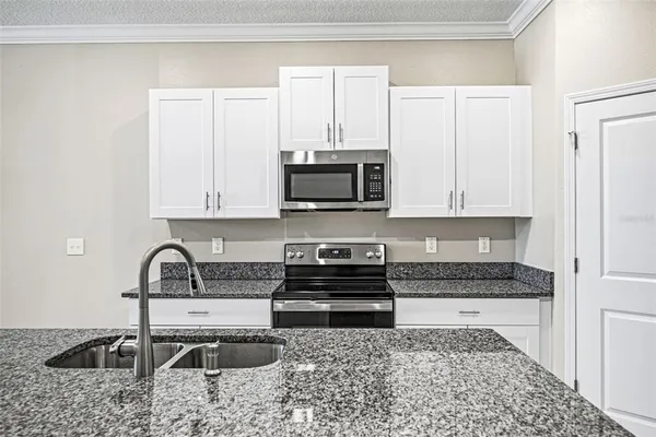 a kitchen with granite countertop a sink and a stove top oven