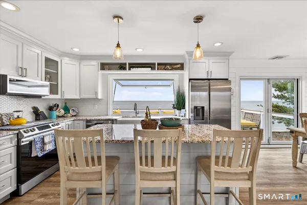 a kitchen with stainless steel appliances granite countertop a stove a refrigerator a kitchen island a stove a dining table and chairs