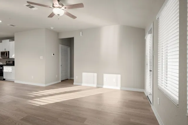 a view of an empty room with wooden floor and a window