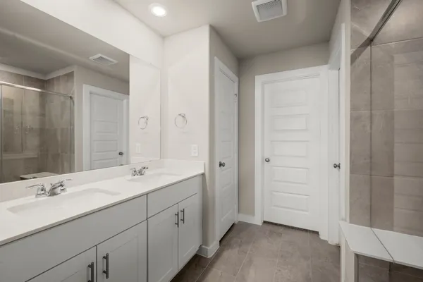 a spacious bathroom with a double vanity sink a large mirror and shower