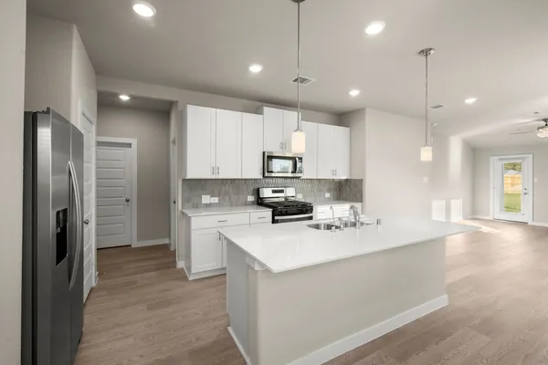 a kitchen with a sink a refrigerator a stove and kitchen island with wooden floor