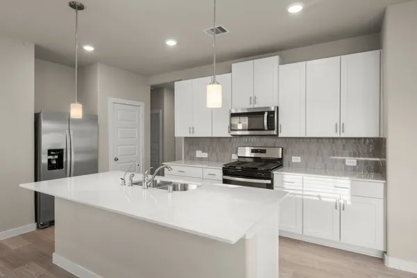a kitchen with kitchen island a sink stainless steel appliances and white cabinets