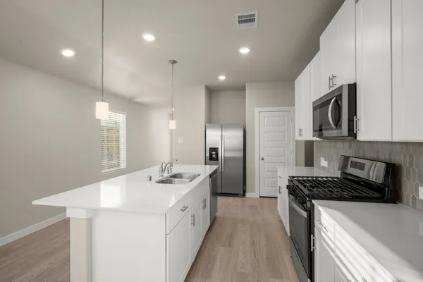 a kitchen that has a sink a stove and chairs
