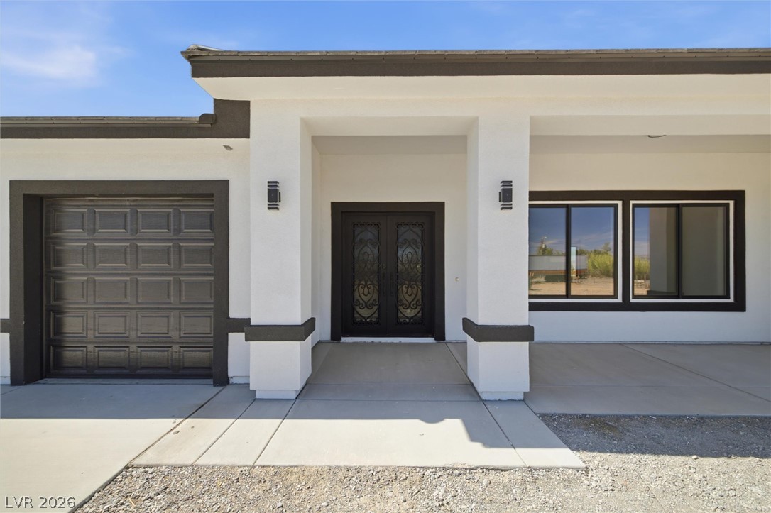 5910 East Kellogg Road Pahrump, NV 89061 - Photo 6 of 58 A modern facade with striking dark entry doors and a matching garage, framed by crisp white stucco.