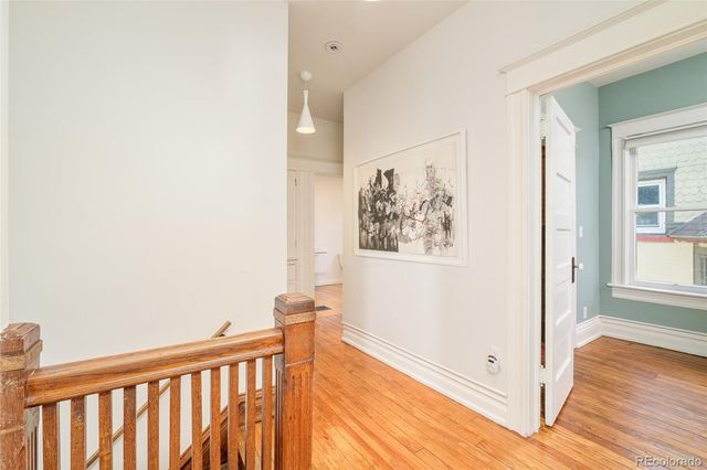 a view of a hallway with wooden floor and a bathroom