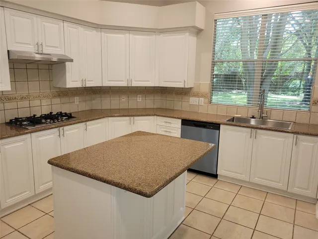 a kitchen with granite countertop a sink a stove and cabinets