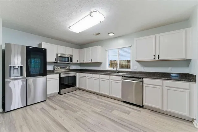 a kitchen with granite countertop white cabinets and stainless steel appliances