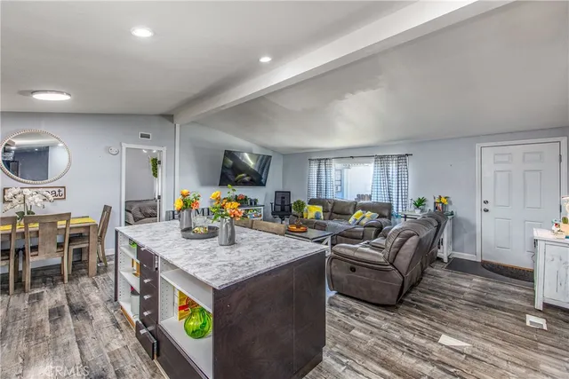 a kitchen island with stainless steel appliances granite countertop wooden floor a stove top oven a granite counter space and furniture