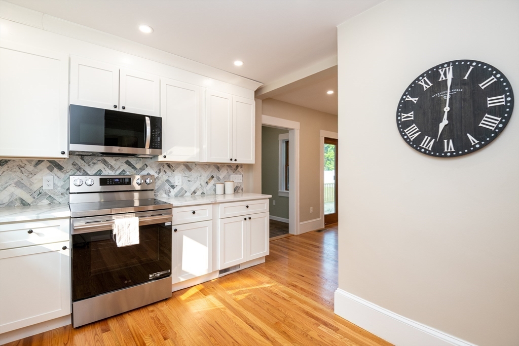 179 Lions Mouth Road Amesbury, MA 01913 - Photo 9 of 42 a kitchen with stainless steel appliances kitchen island granite countertop a stove and a sink