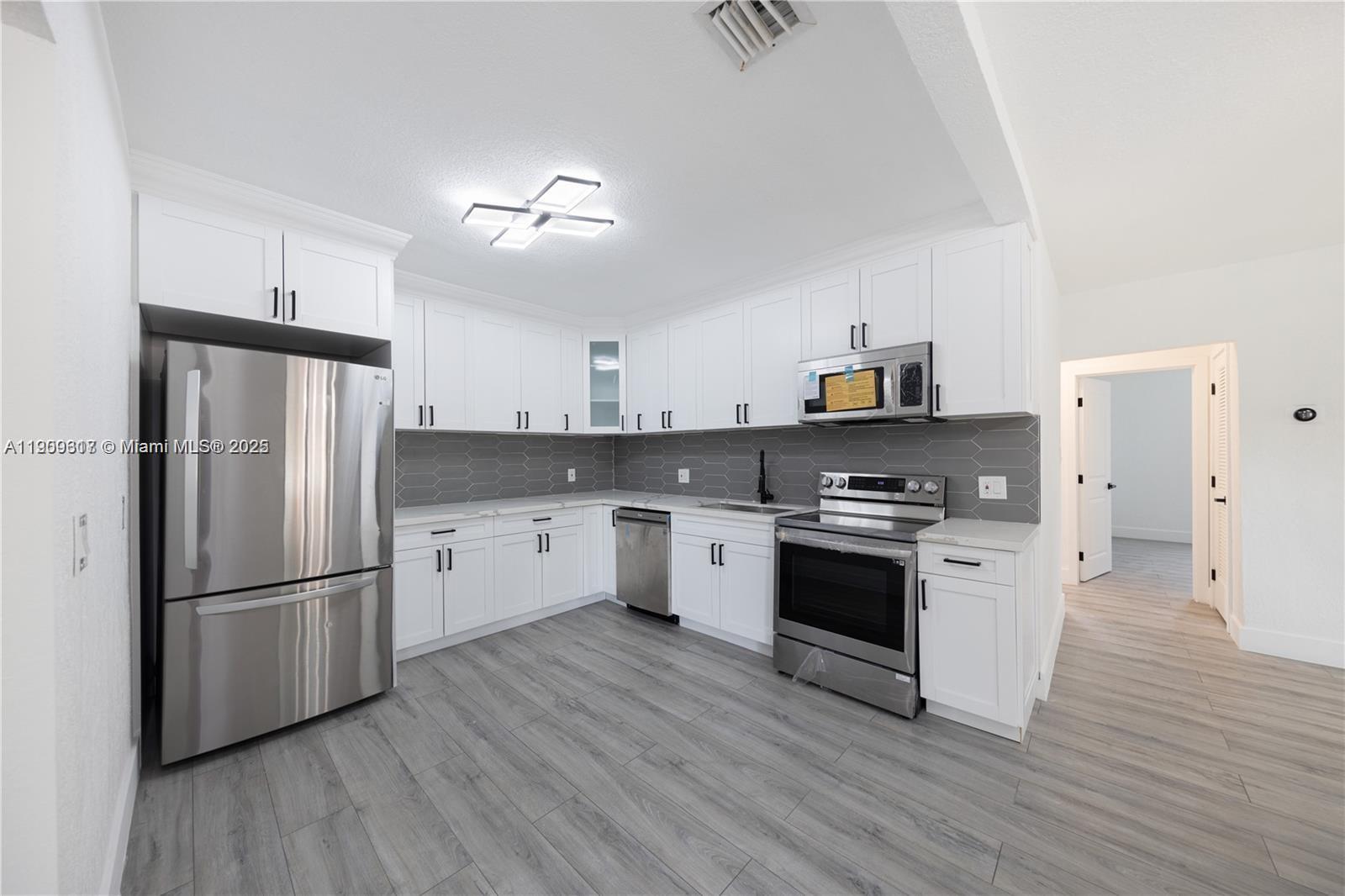 271 Northwest 143rd Street Miami, FL 33168 - Photo 11 of 43 a kitchen with white cabinets stainless steel appliances and wooden floors