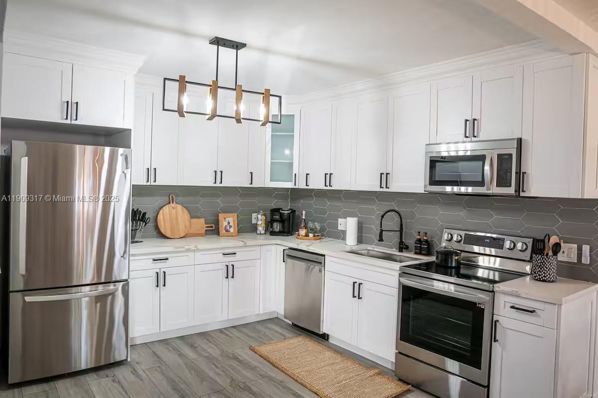 271 Northwest 143rd Street Miami, FL 33168 - Photo 12 of 43 a kitchen with stainless steel appliances granite countertop a refrigerator stove a sink dishwasher and white cabinets with wooden floor
