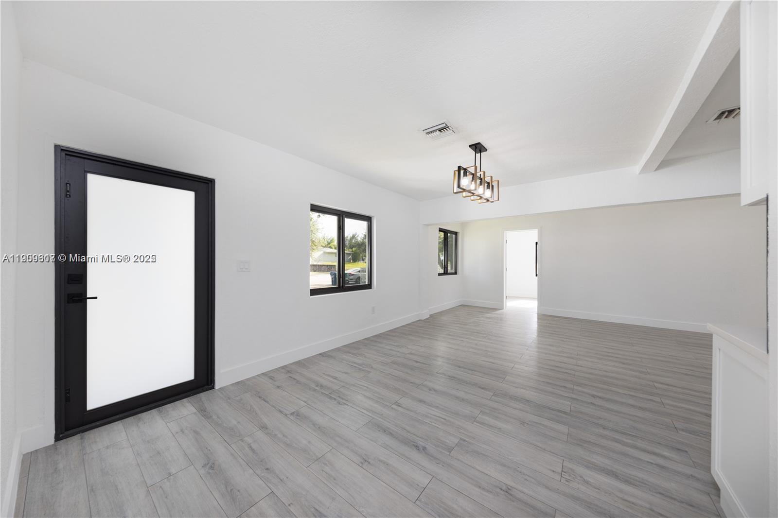 271 Northwest 143rd Street Miami, FL 33168 - Photo 13 of 43 an empty room with wooden floor chandelier and windows