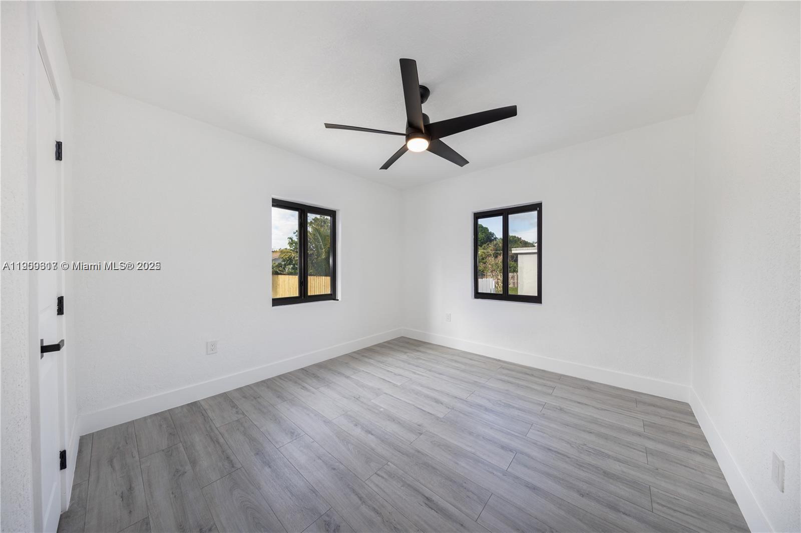 271 Northwest 143rd Street Miami, FL 33168 - Photo 22 of 43 an empty room with wooden floor ceiling fan and windows