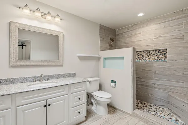 a bathroom with a granite countertop toilet sink and mirror