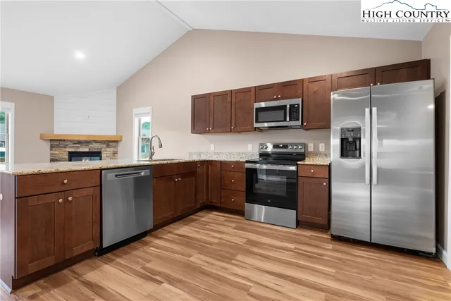 a kitchen with granite countertop a refrigerator and a stove top oven
