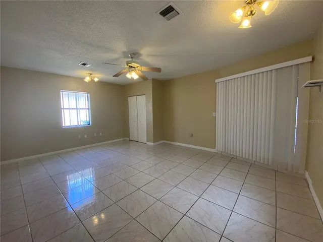 an empty room with windows and chandelier fan
