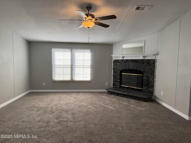 an empty room with windows and fireplace