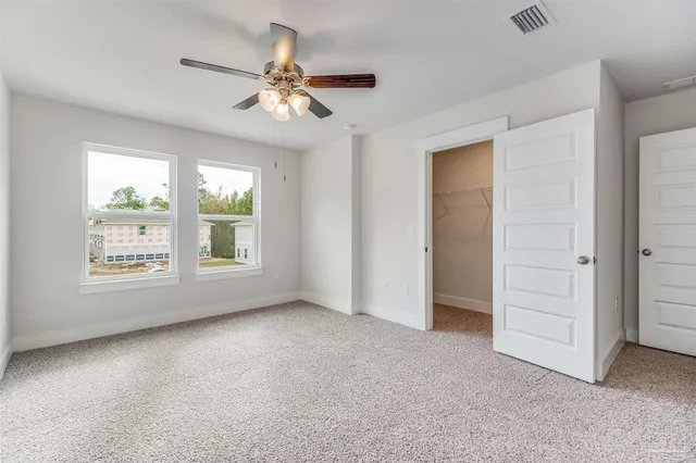 an empty room with windows and fan