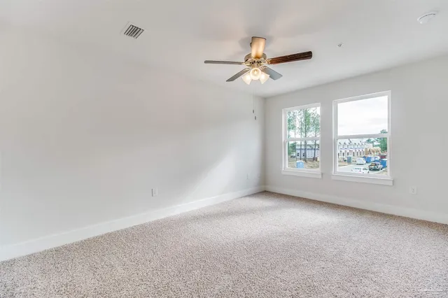 an empty room with windows and fan