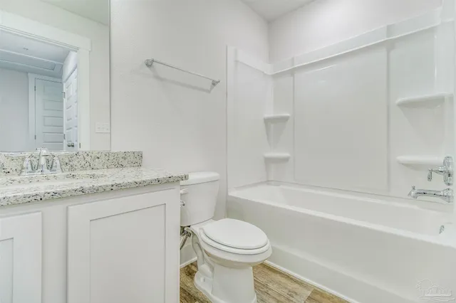 a bathroom with a granite countertop sink a toilet and shower