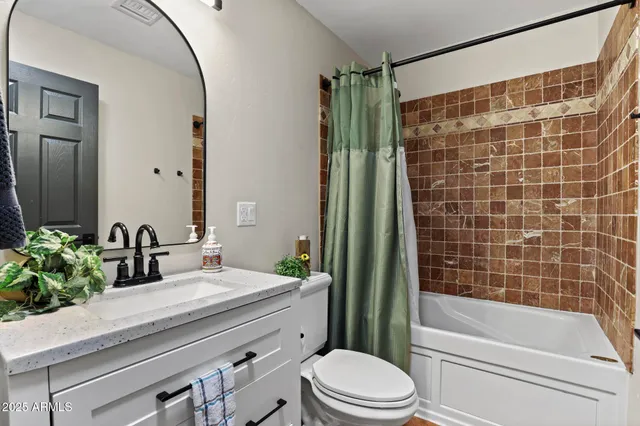 a bathroom with a granite countertop sink a toilet a mirror and shower