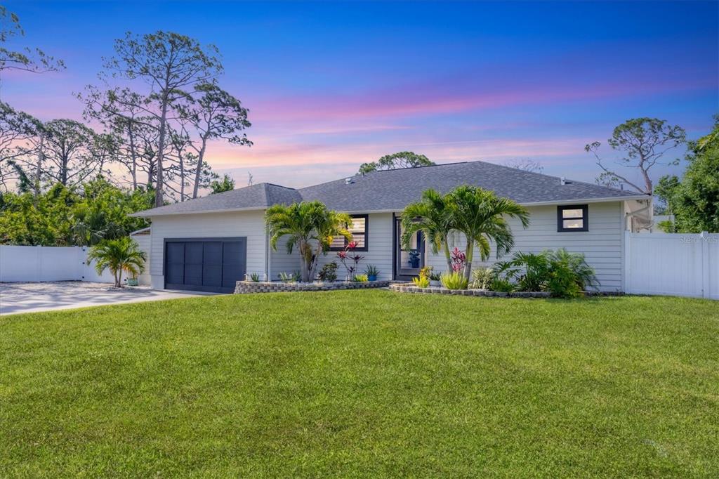 a front view of a house with a garden and tree
