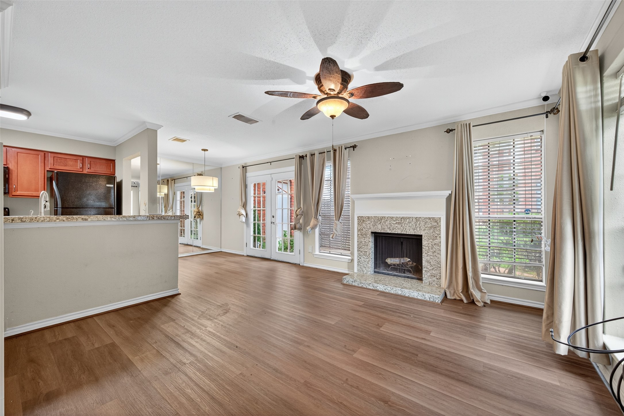 2211 South Kirkwood Road, Unit 49 Houston, TX 77077 - Photo 9 of 34 a view of a kitchen and an empty room with wooden floor a ceiling fan