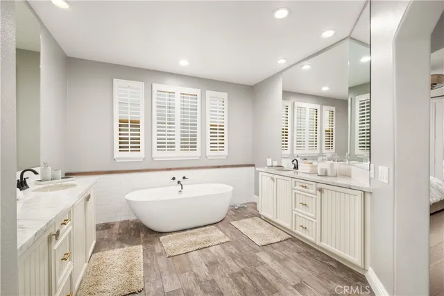 a bathroom with a granite countertop sink a mirror a bathtub and shower