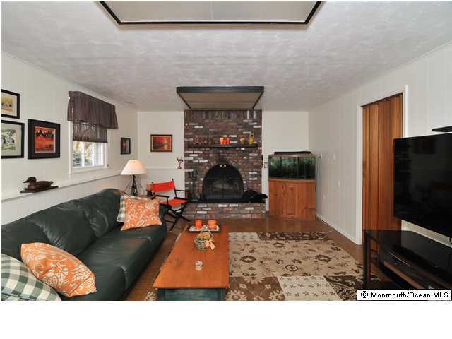 861 Colts Neck Road Freehold, NJ 07728 - Photo 22 of 25 a living room with furniture a fireplace and a flat screen tv