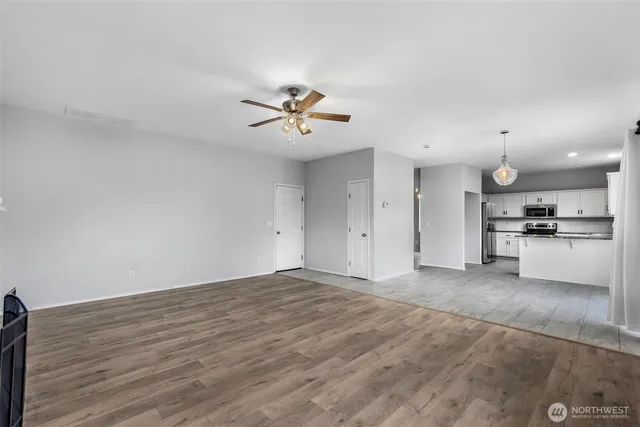a view of an empty room with kitchen and kitchen view