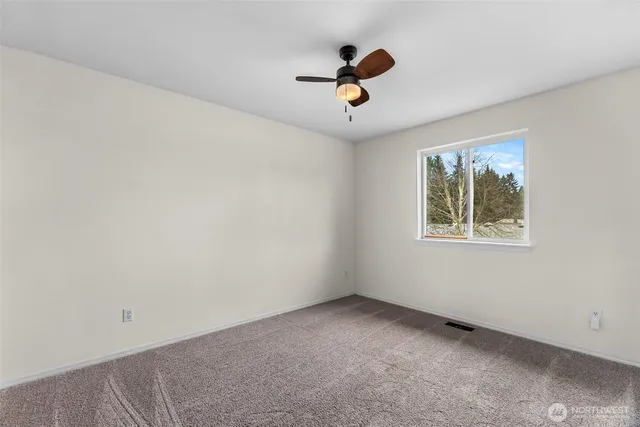 an empty room with a window and a fan