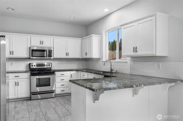 a kitchen with stainless steel appliances granite countertop a stove a sink and a microwave